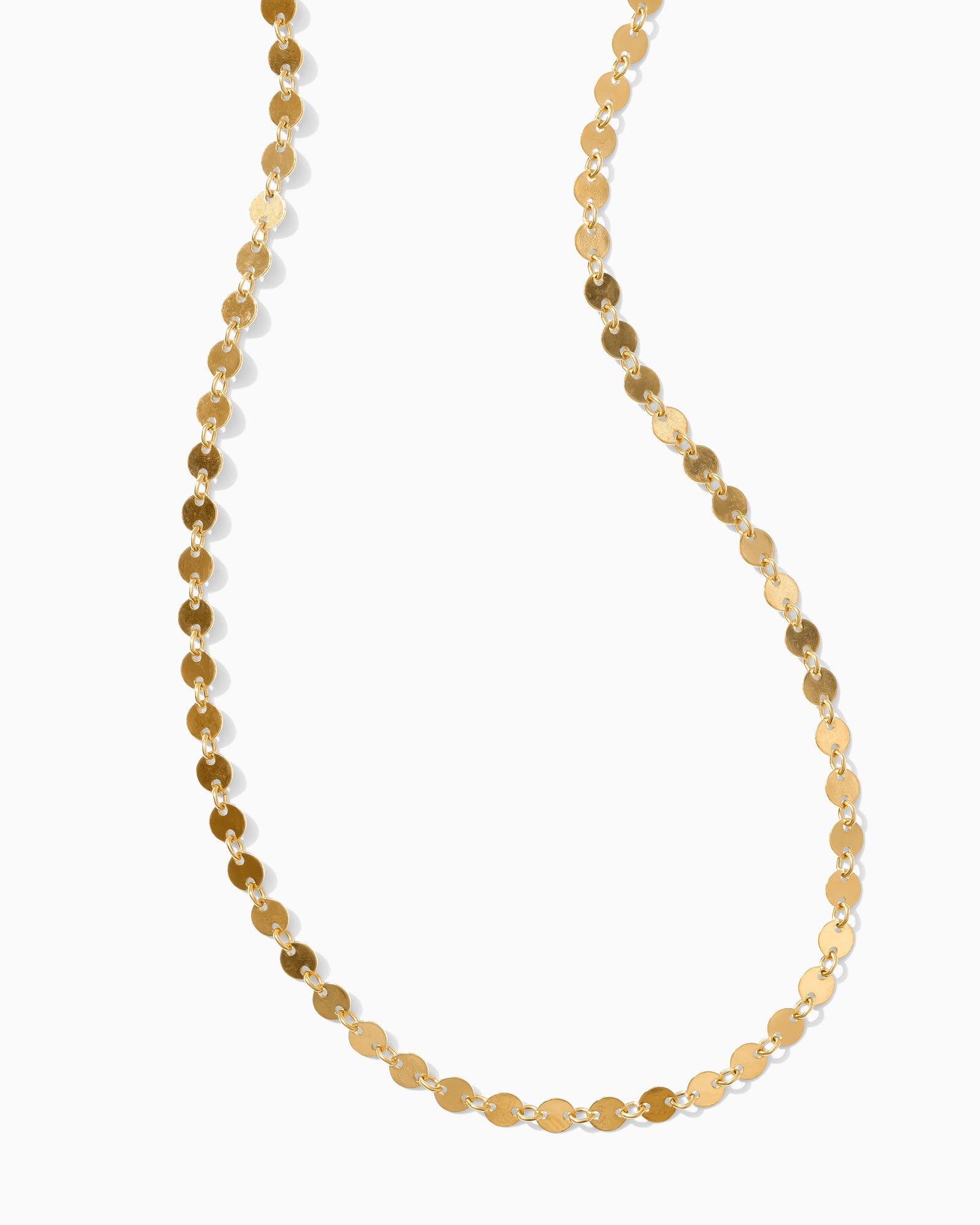 Gold chain necklace with small, flat, round disc links shimmering against a white background
