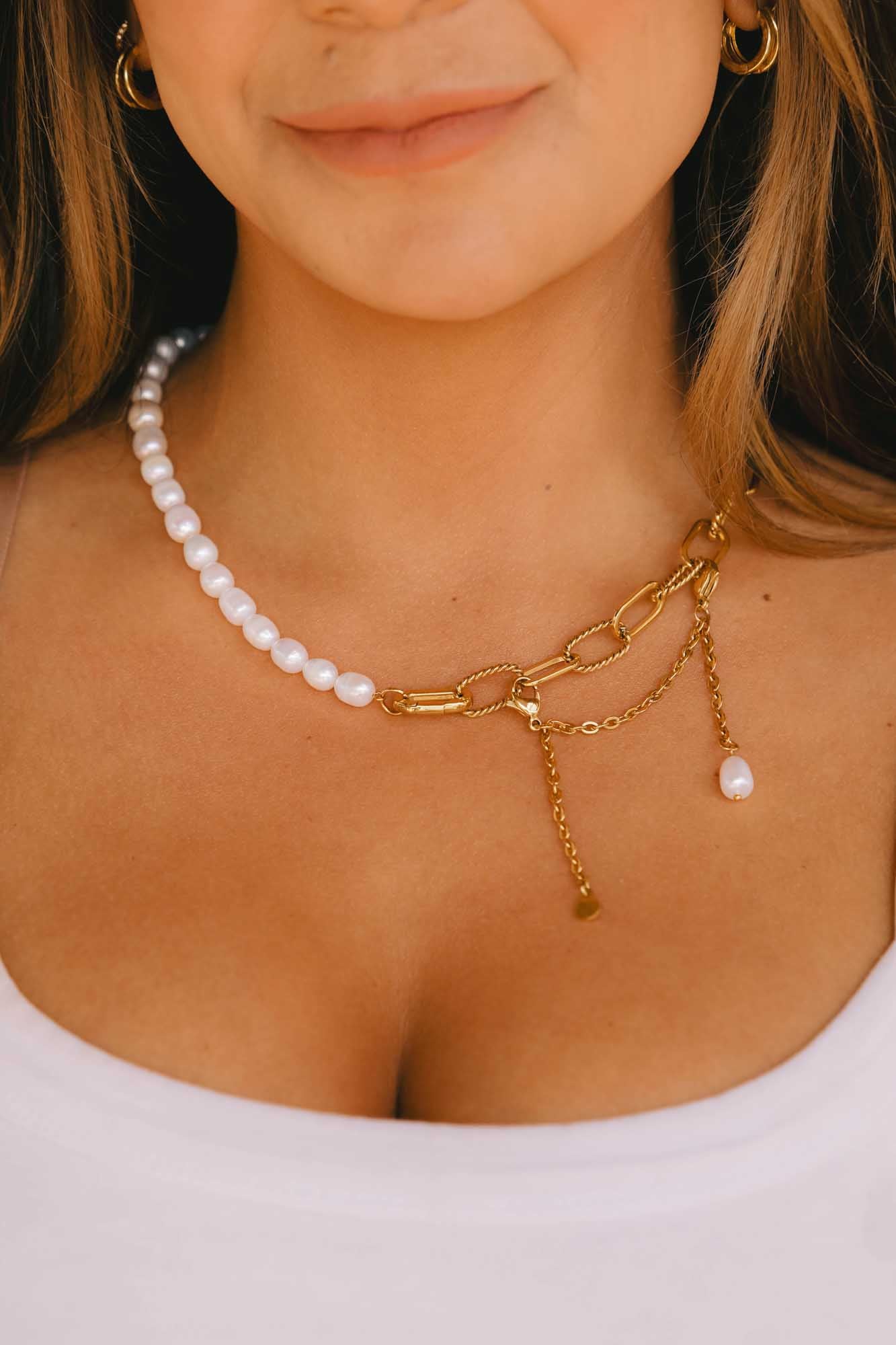 Close-up of a person wearing a pearl and gold chain necklace.