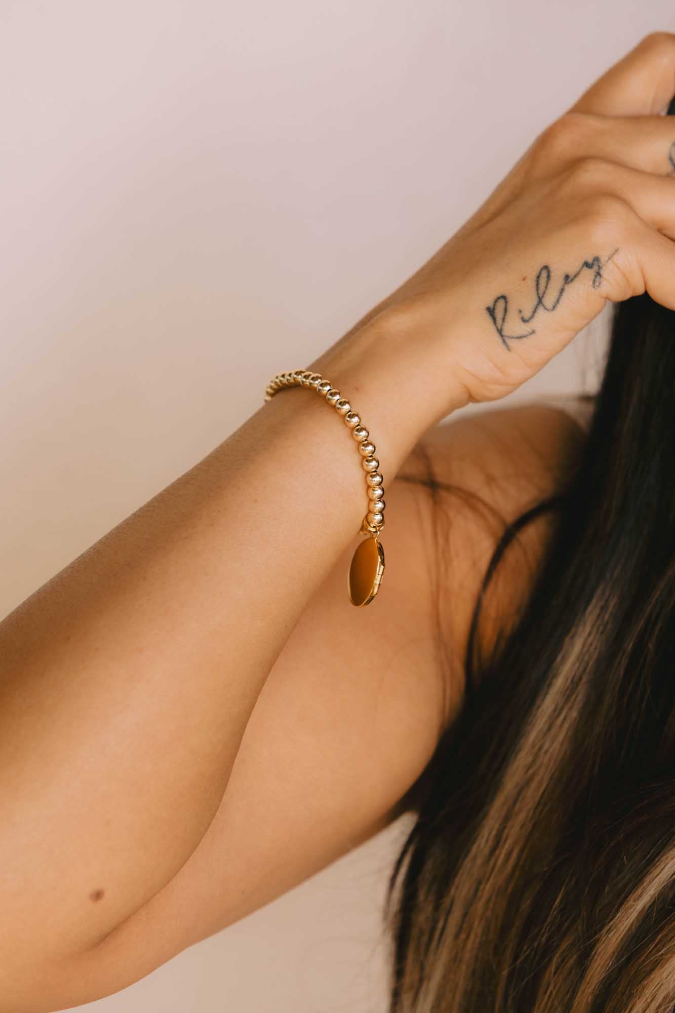 Close-up of a hand wearing a gold bracelet with a blurred background