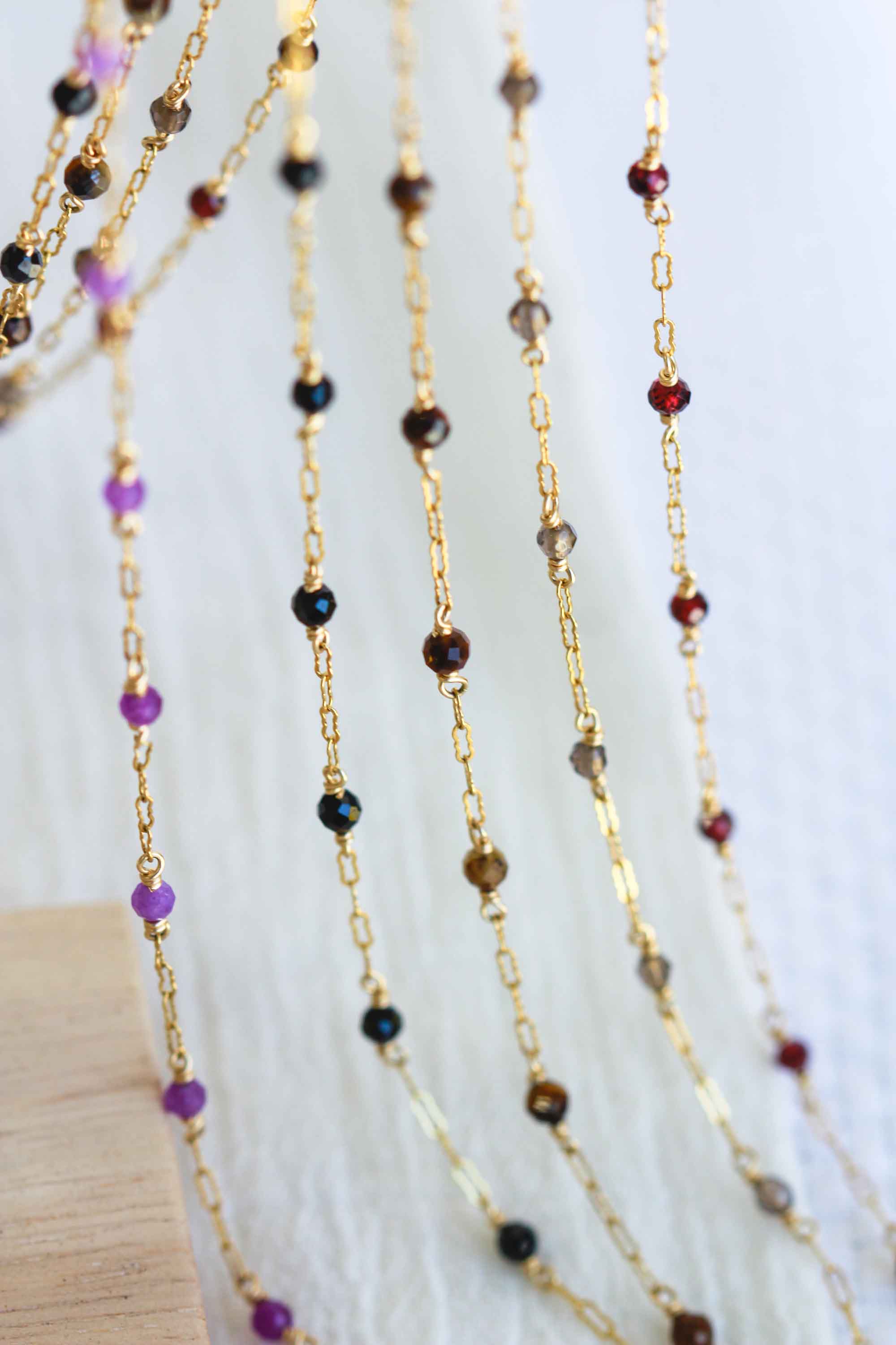 Gold chain necklaces with multicolored beads on a white background.