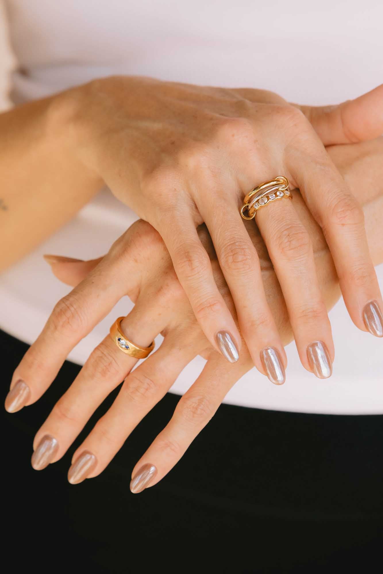 Close-up of a manicured hand wearing gold rings