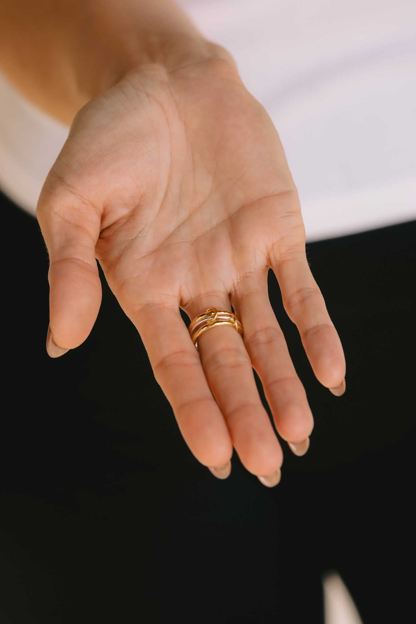 Close-up of a hand wearing gold rings with white and black background