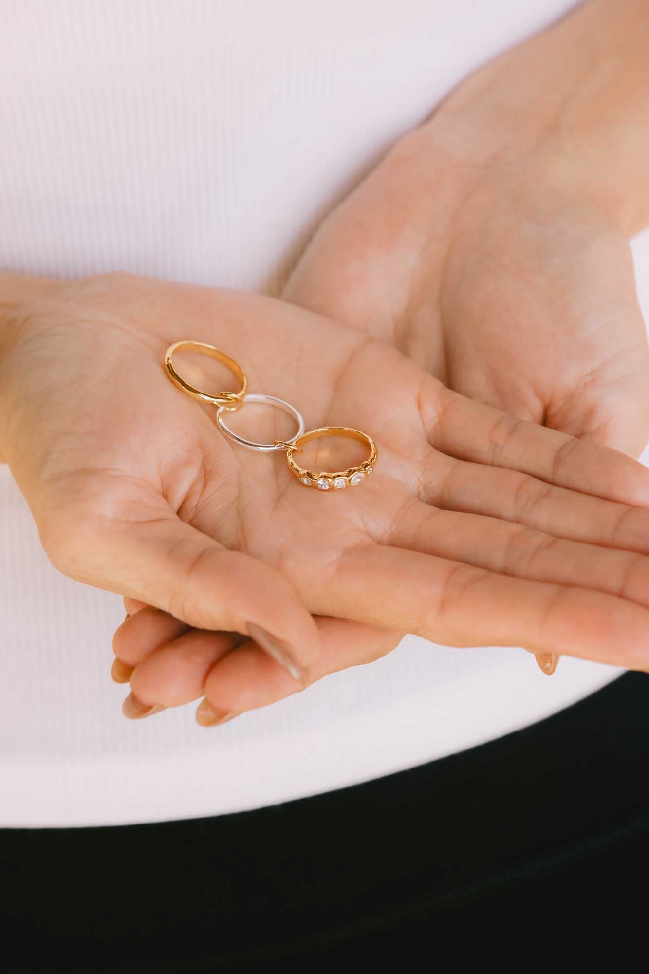 Close-up look of a manicured hand displaying two gold rings and one silver ring