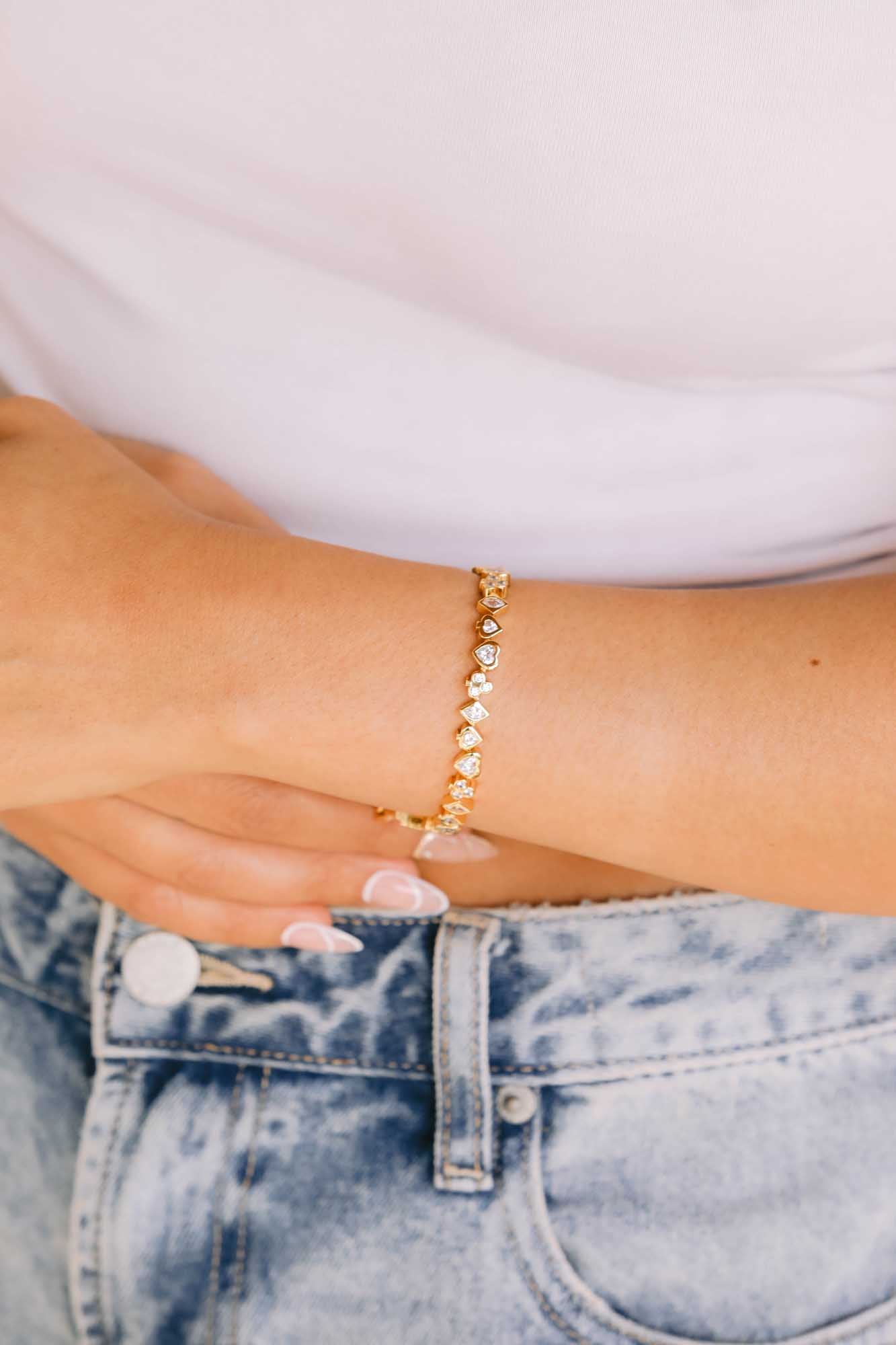 Close up of a gold bracelet on white and blue jean's background