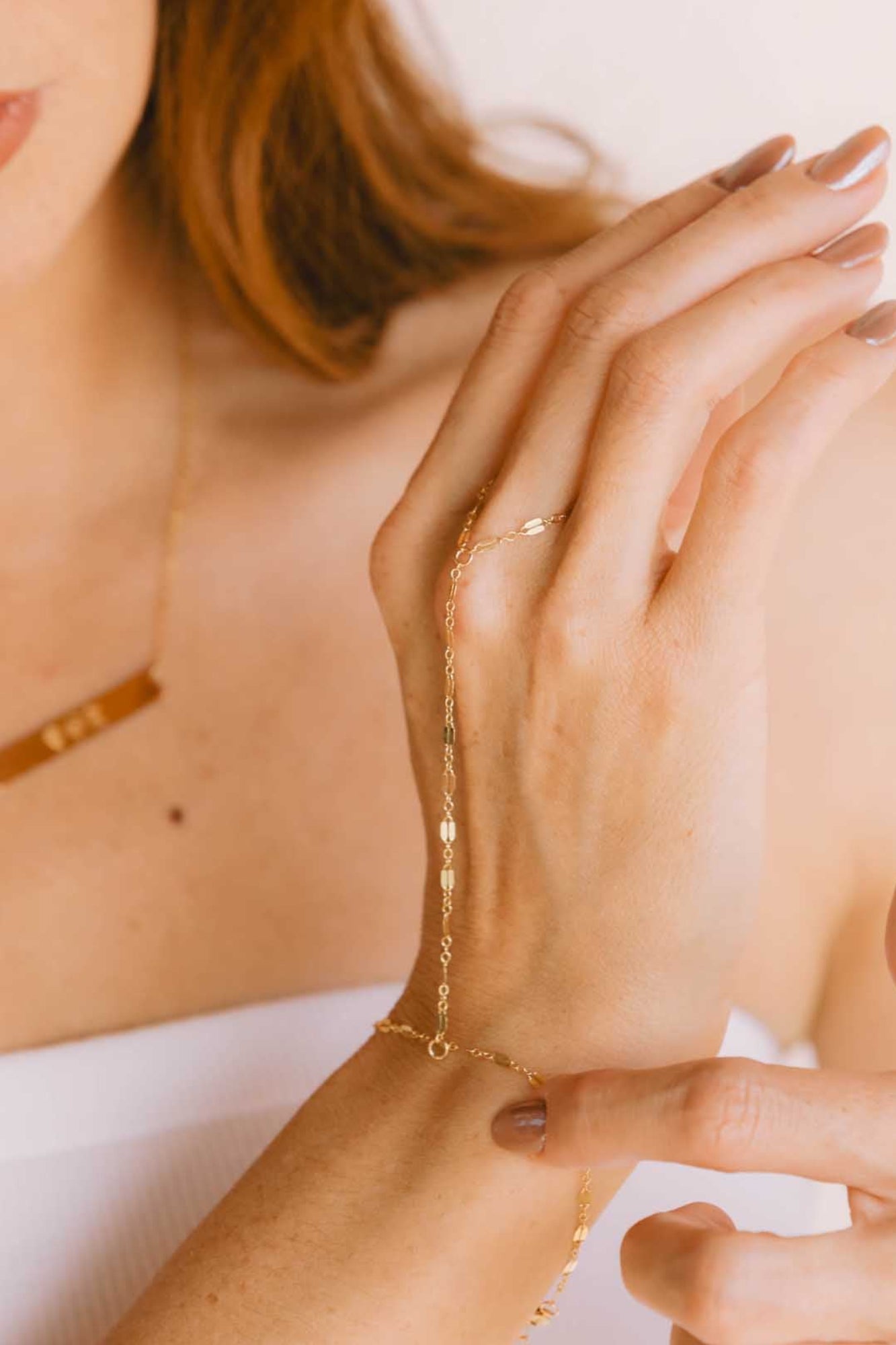 Hand close up wearing gold bracelet extended to middle finger.