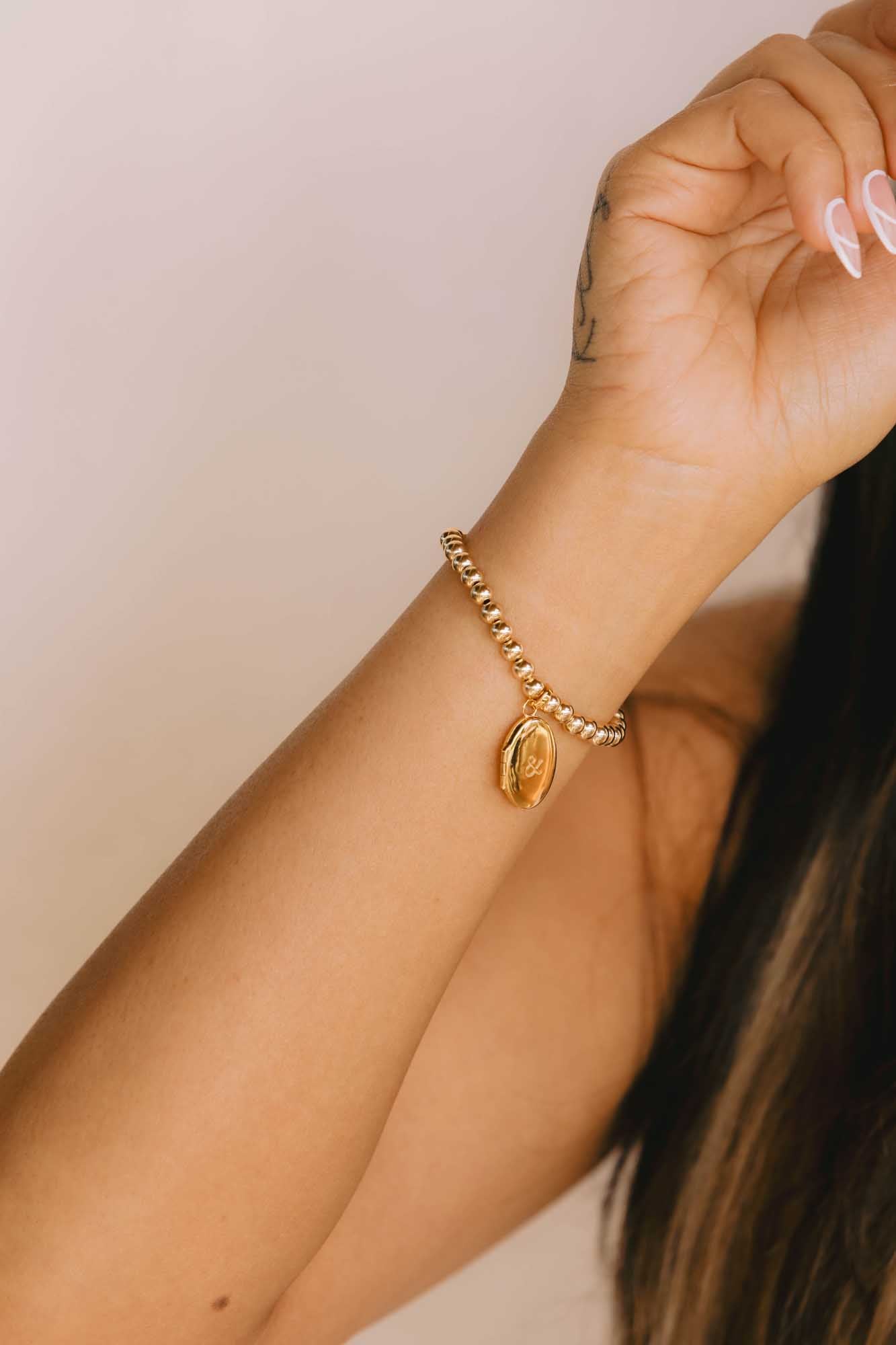 Gold bracelet on a wrist with a neutral background