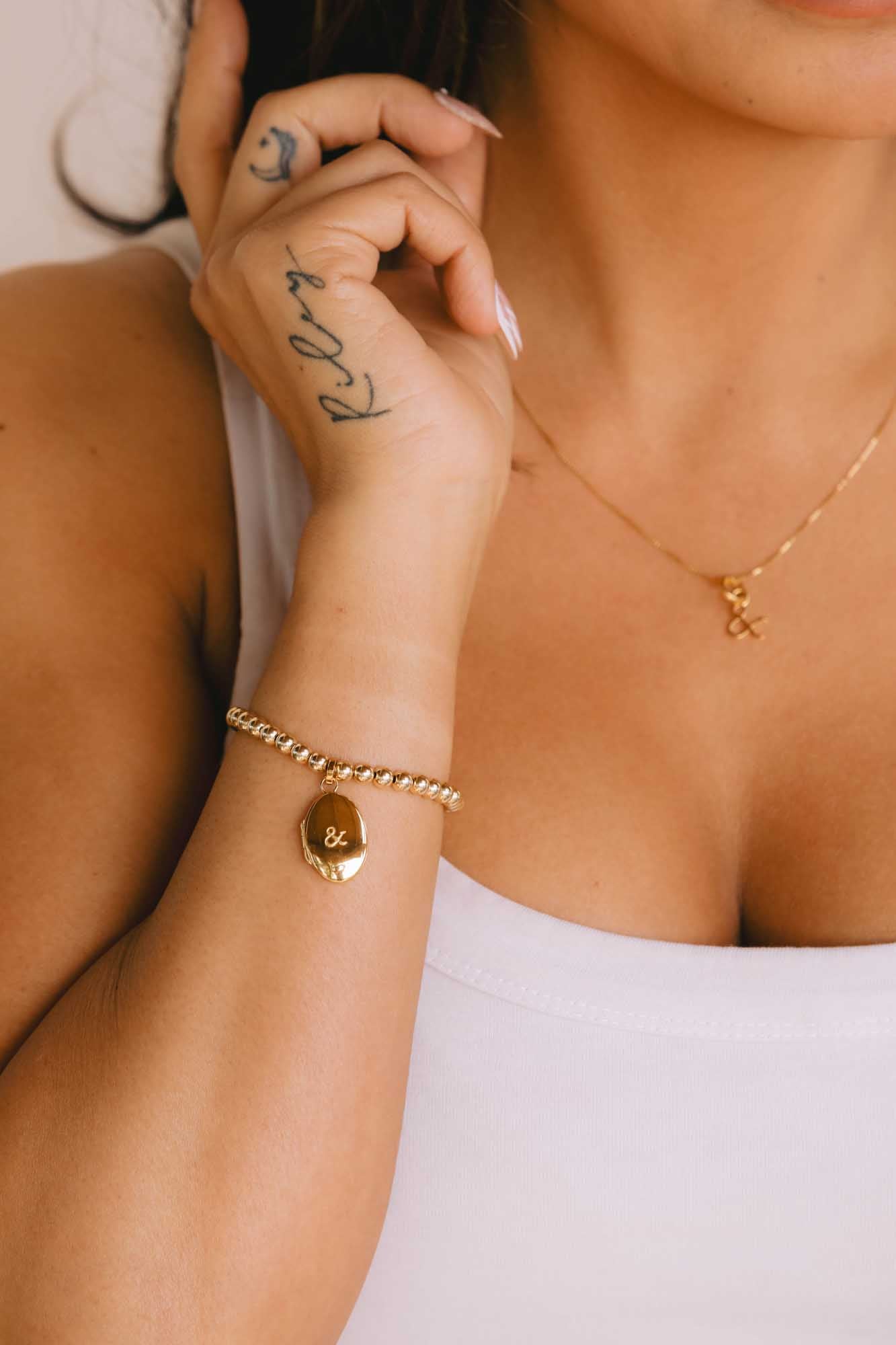 Close-up of a person wearing gold jewelry including a necklace, bracelet, and ring.