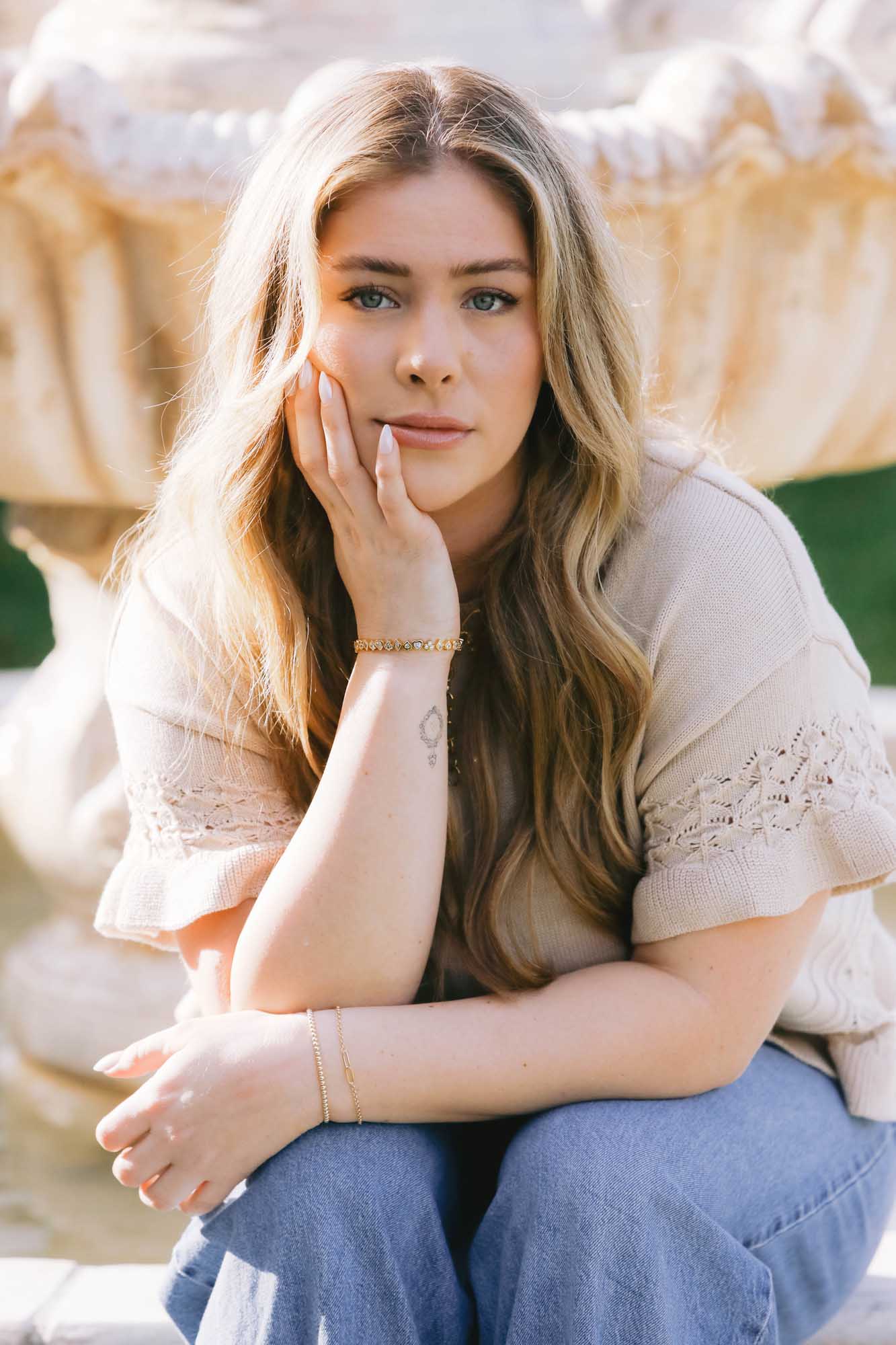 Woman sitting outdoors leaning on hand with bracelets on each wrist