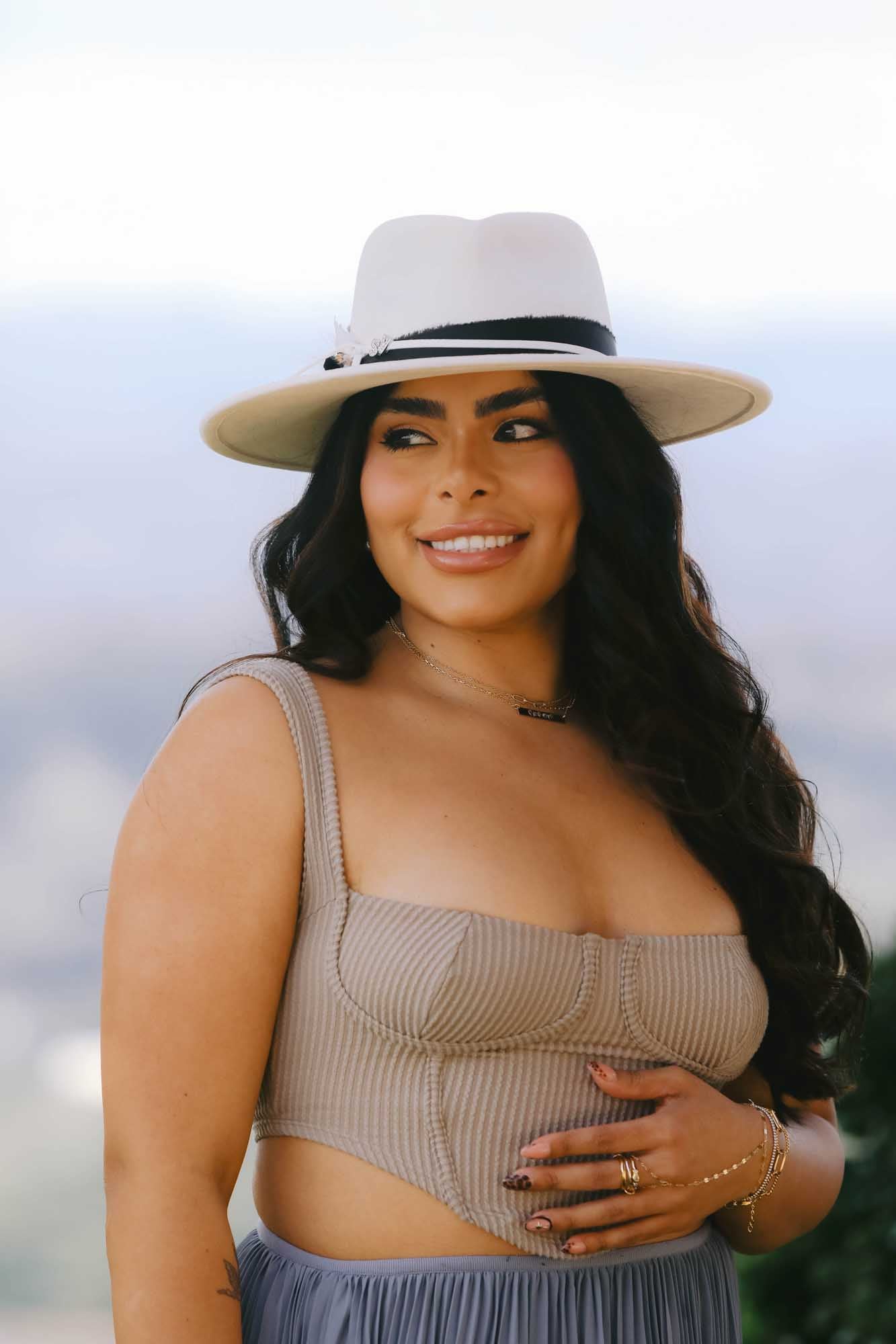 Woman wearing a wide-brimmed hat with necklace, ring, and bracelets.
