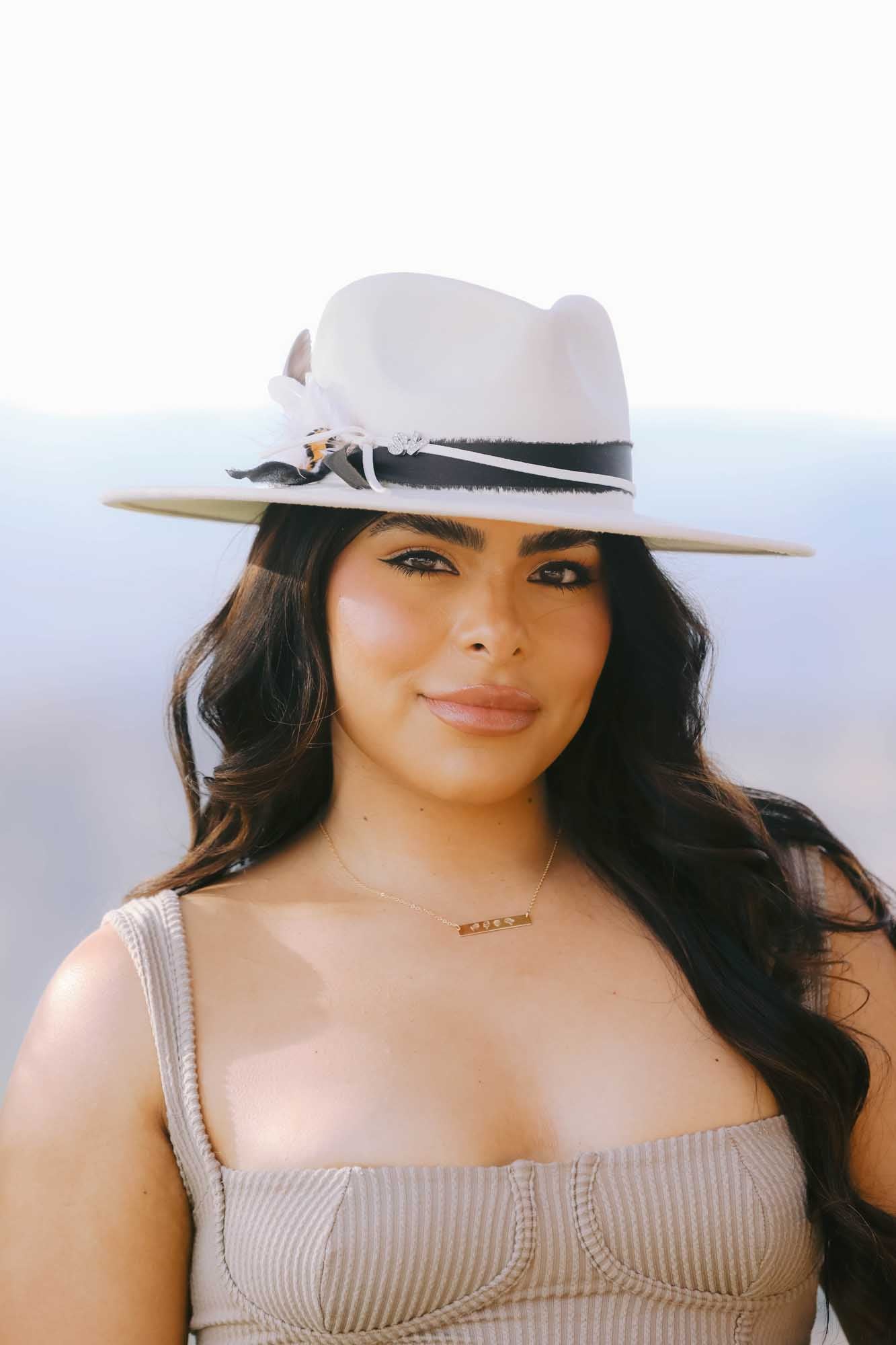 Woman wearing a gold necklace on a light background.