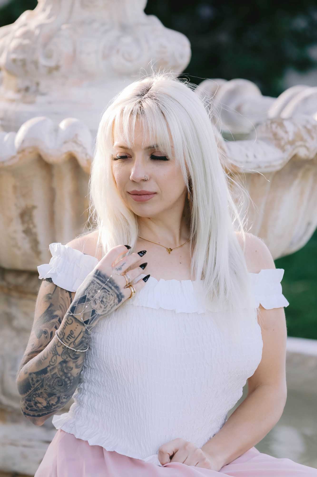 Woman sitting by a fountain wearing multiple gold rings and silver bracelet